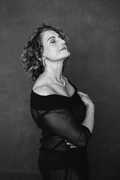 A stunning older woman poses with her eyes closed and arms wrapped around herself