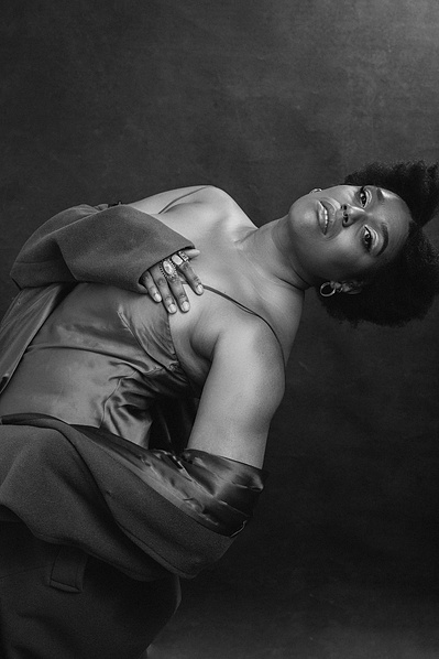 A beautiful black woman arches backwards into the frame, a hand resting on her chest