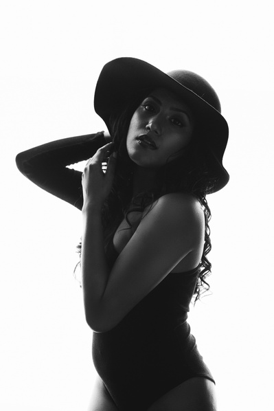 Slim Asian woman wearing a hat, she is backlit and mostly silhouetted