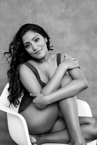 Stunning asian woman with long curled hair sits on a white chair