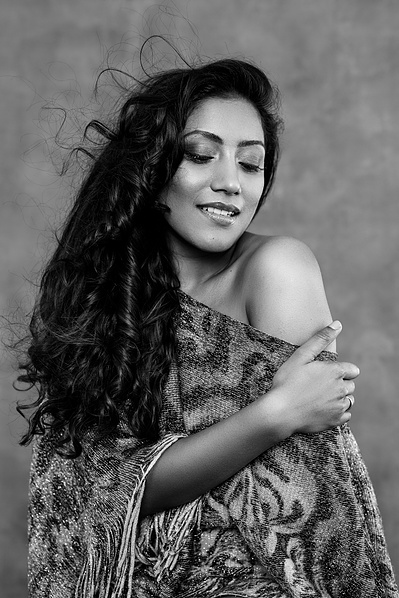 Stunning Asian woman looks coyly down as she slips a kaftan off one shoulder