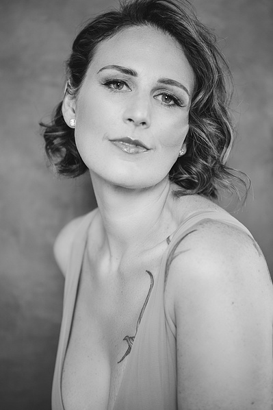 A striking brunette woman looks enigmatically at the camera