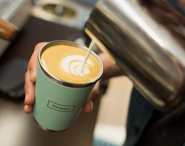 Close up photo showing a barista pouring milk into a coffee cup