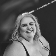 A curvaceous blonde woman in lingerie beams at the camera