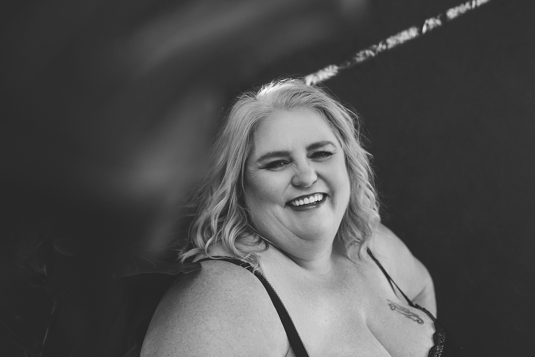A curvaceous blonde woman in lingerie beams at the camera