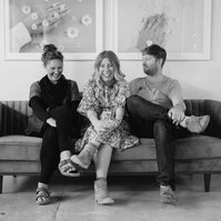 Three colleagues sit on a sofa, something has made them laugh out loud