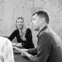 Three colleagues sit around a meeting table, they are having a lively and positive discussion
