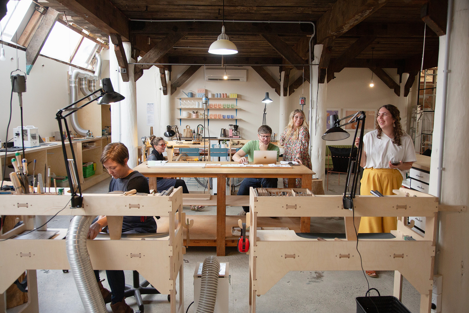 A large jewelry workshop filled with five workers, all on different tasks