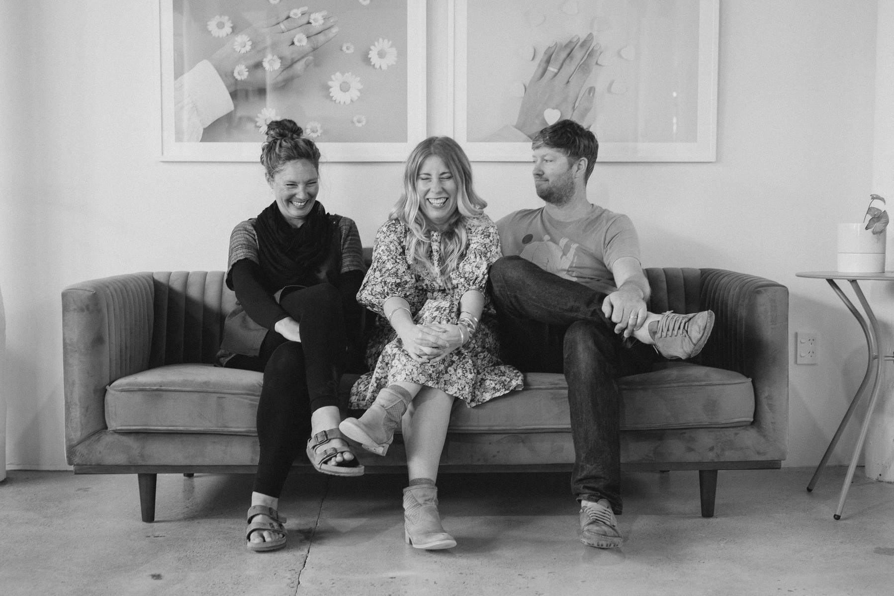 Three colleagues sit on a sofa, something has made them laugh out loud