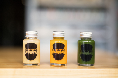Three smoothies in glass jars sit on a wooden benchtop
