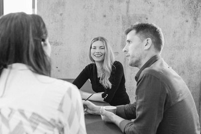 A team of people sit around a table, smiling as they discuss