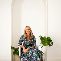 A slim blonde woman sits in a chair in a photography studio