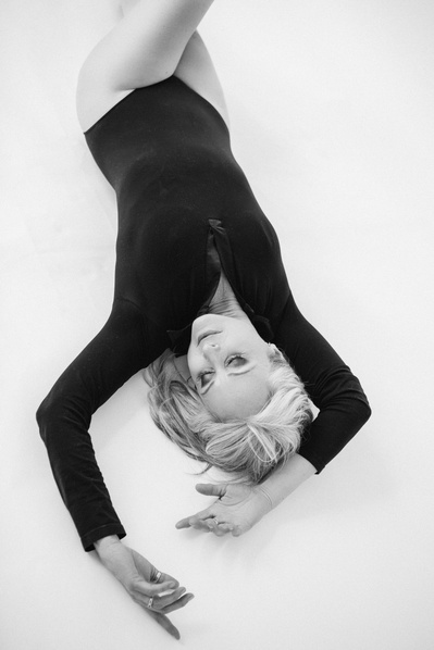 A glamourous blonde woman reclines, her arms thrown above her head