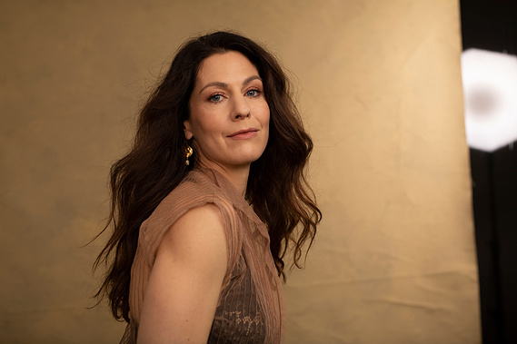 A glamourous older brunette woman stares into the camera