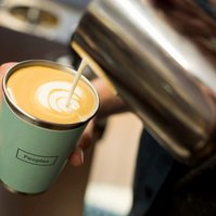 A barista pours milk into a cup of coffee
