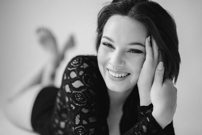 A young brunette woman lays down, smiling at the camera