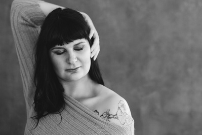 A woman wears jumper dress with one tattooed shoulder visible