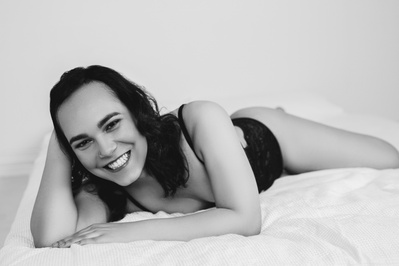A woman lies on a bed, one hand used to prop her head up