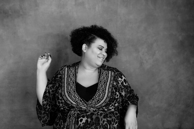 A curvaceous black woman wears a kaftan and dances with abandon