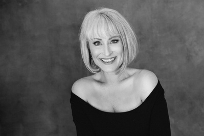 A glamourous older blonde woman smiles broadly at the camera