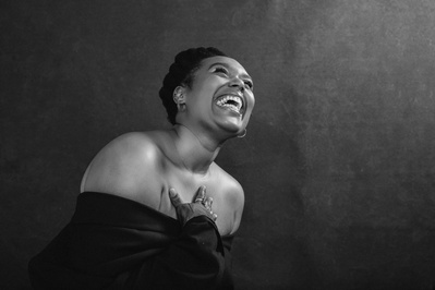 A woman photographed from below, arms wrapped around herself as she laughs