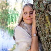 A woman leans against a willow tree, her eyes closed