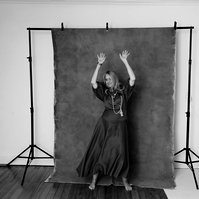 A woman laughs and dances with abandon in front of a photo backdrop