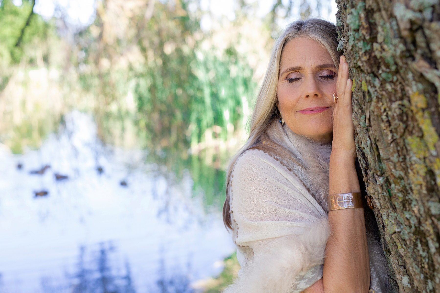 A woman leans against a willow tree, her eyes closed