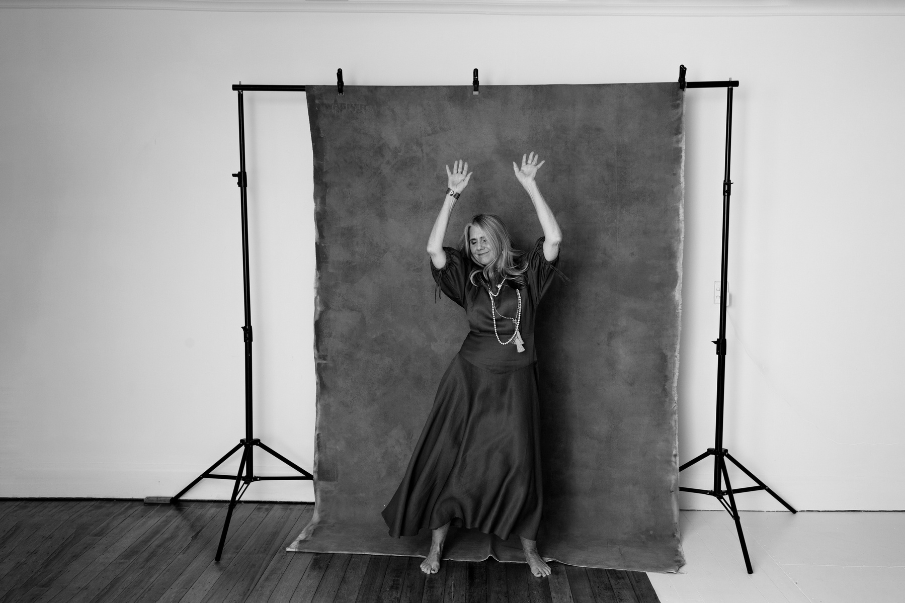 A woman laughs and dances with abandon in front of a photo backdrop
