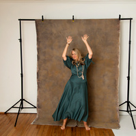 A slim blonde woman dances in front of a photography backdrop