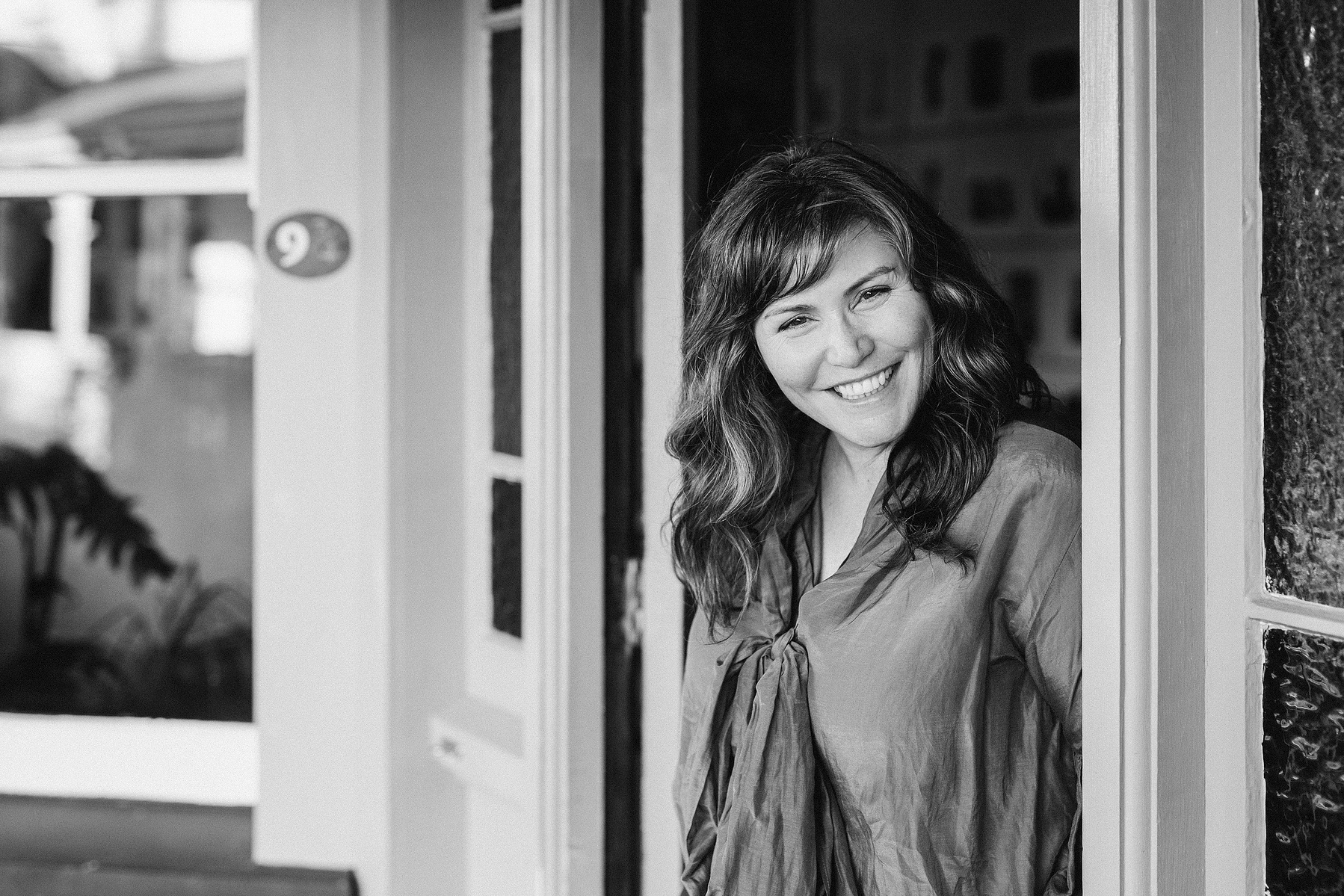 A brunette photographer peeks out of the door in a Nelson photography studio