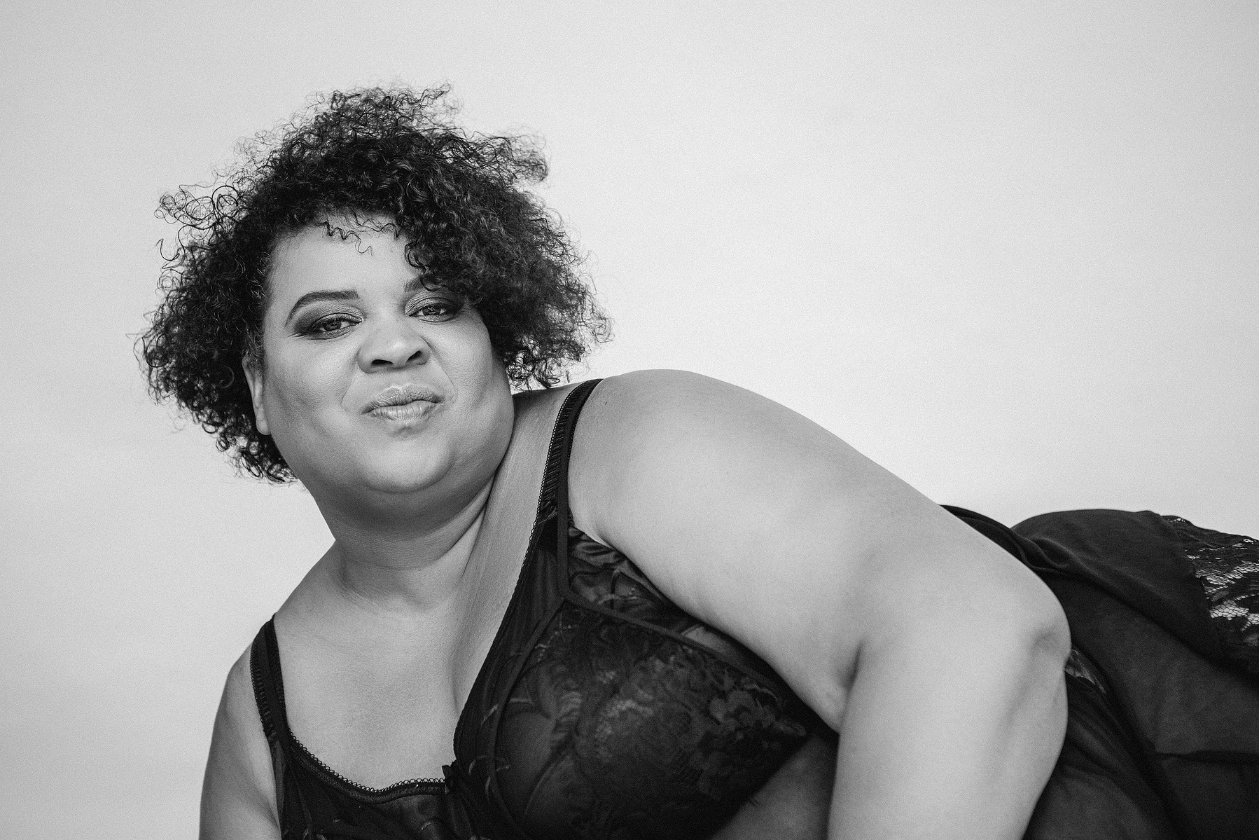 A stunning woman pouts at the camera, she is reclined onto a bed