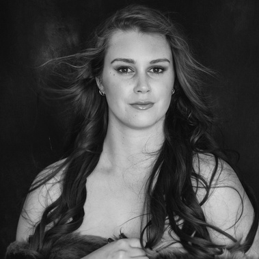A young curvy woman stares into the camera, she looks powerful