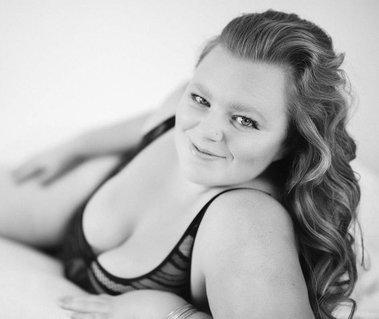 Beautiful curvy woman in body suit lingerie laying on her bed on her side. 