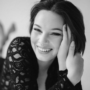 Happy young woman wearing bodysuit with her face in her hands.
