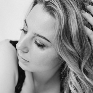 A young white woman is photographed in a boudoir style, her face is in focus 