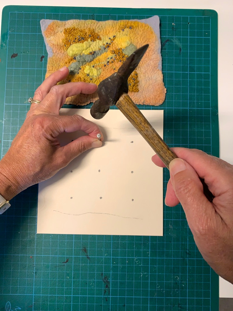 keep making holes until all the pencil marks have been done then the wet felted artwork can be strung onto the card. Lynn Comley prepares her artwork like this before framing