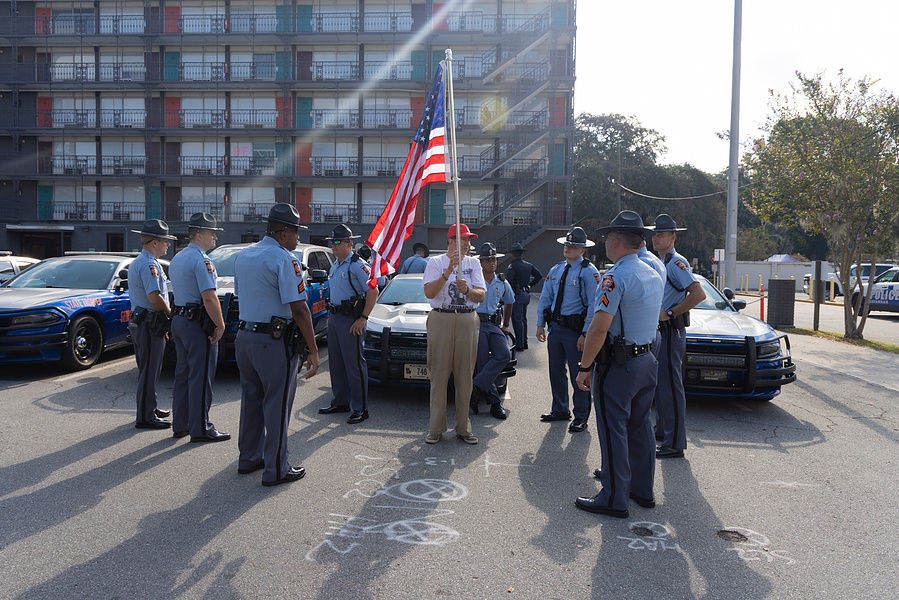 Group of police officers awkwardly surround a friendly Trump Supporter who was walking around before Donald Trump’s rally in Savannah, GA, September 2024
