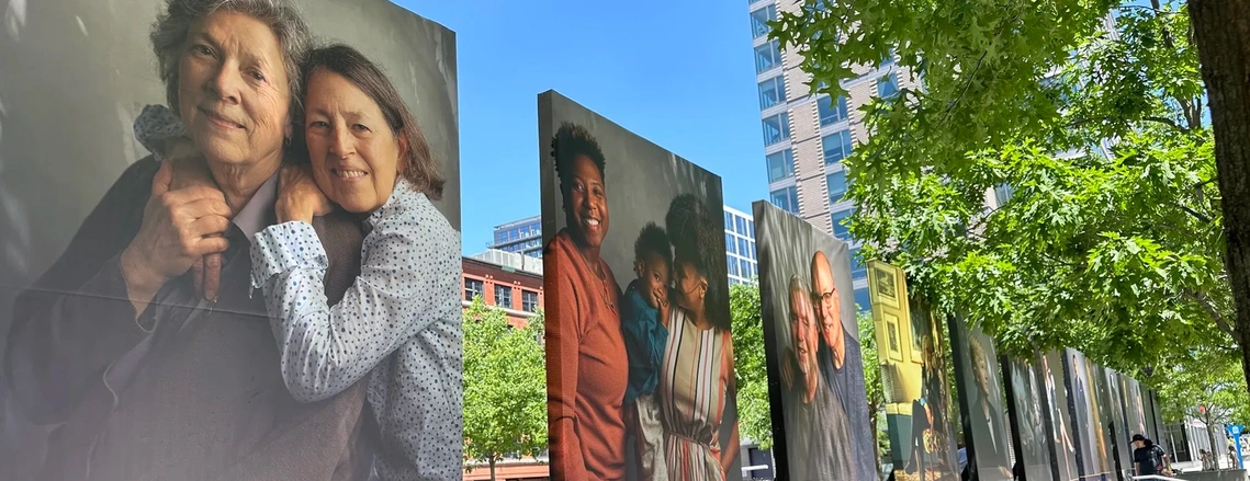 A photo showing a park with portraits printed large-scale on vinyl, displayed for pedestrians.