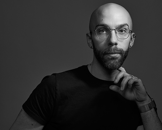 Black and white photo of a young man in glasses and a black t-shirt. Editorial portrait photography by Ben Flythe, Boston.