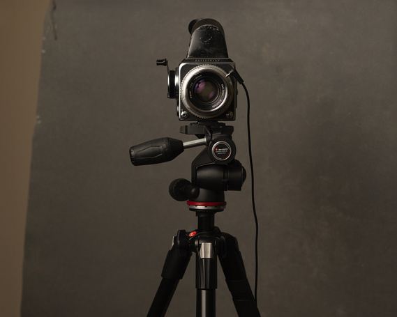 Photo of a Hasselblad 500C film camera on a tripod in front of a grey canvas backdrop.