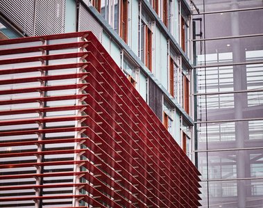 Sharp lines of the goverment building, Jakob-Kaiser-Haus. The building is glass to the right with red horizontal shutter-like detail to the left.