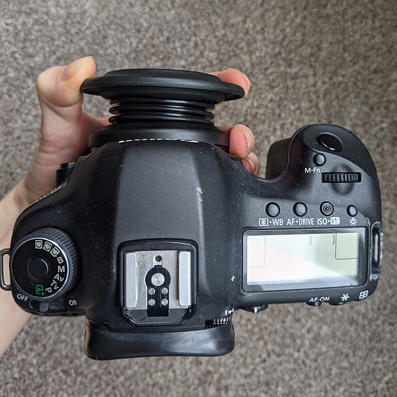 Lensbaby Spark mounted onto the camera. A hand holds the outer rim of the lens so you can see how it pushes in towards the camera to choose focus points