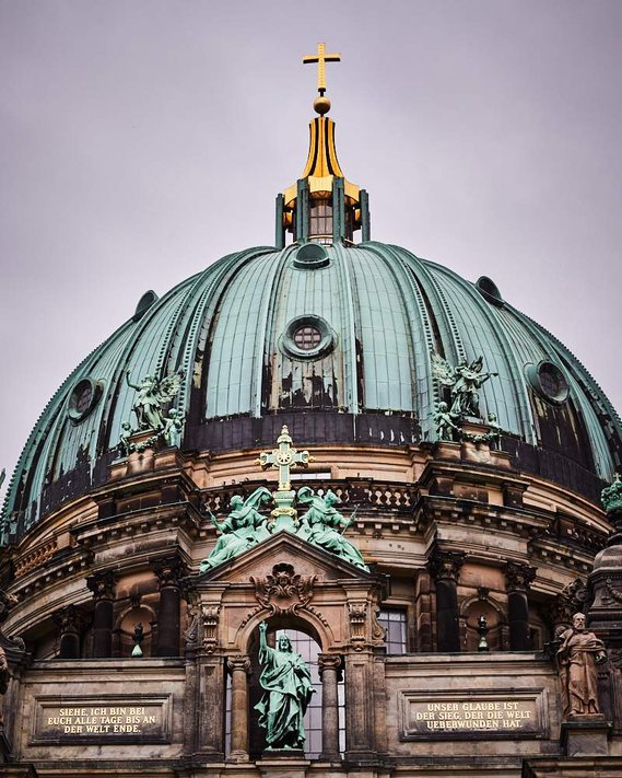 View of the top dome of Berlin Cathedral. There is a gold cross on the top of the turquoise dome