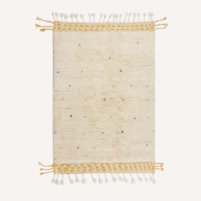 A handmade Moroccan Berber rug with a cream pattern, colourful dots across the design and tassels at the top and bottom