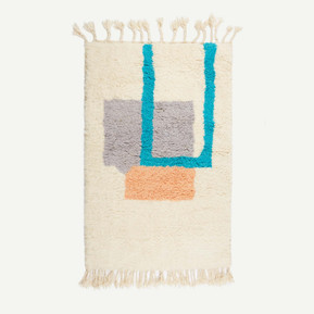 A handmade Moroccan Berber rug with a cream background and squares of cyan, grey-blue and light orange in the centre, and tassels at the top and bottom