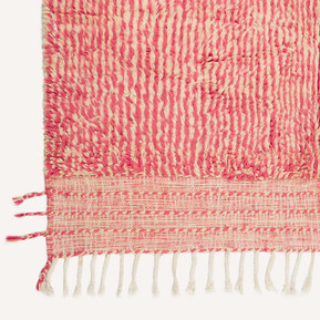 Front detail shot of the corner of a pink and cream Moroccan Berber rug, showing the tassels at the bottom left hand corner