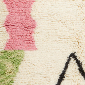 Close-up shot showing the texture of a black, cream, pink and green rug