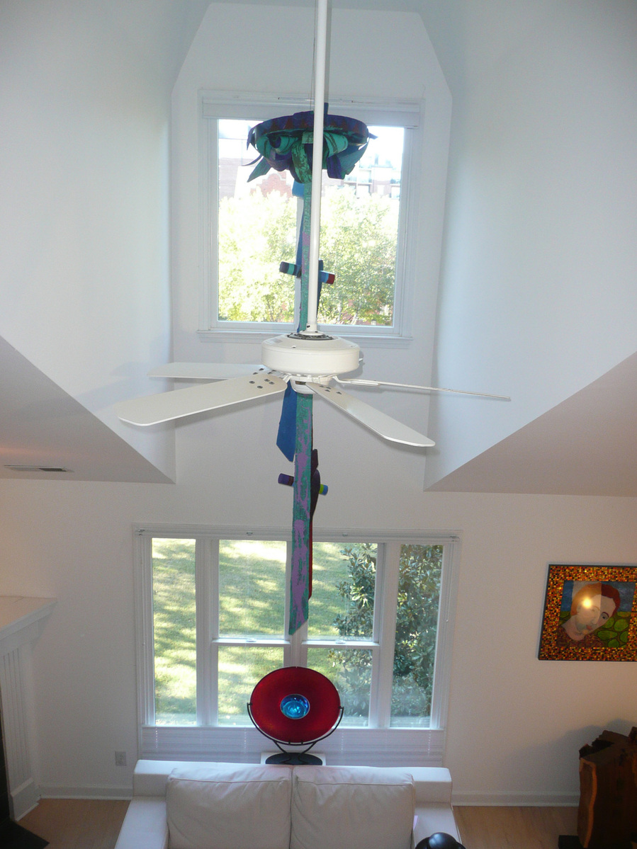 Installation Beyond View- Abstract Art Installation In A Room With White Walls, White Ceiling Fan and Two Large Windows.