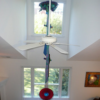 Installation Beyond View- Abstract Art Installation In A Room With White Walls, White Ceiling Fan and Two Large Windows.